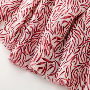 Macro detail of scarf fabric with dark red leaf texture and gold foil rectangle accents