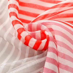 Macro detail of red and white striped lightweight gauze fabric with soft fringe edges