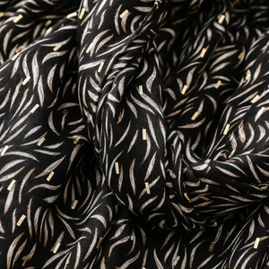 Macro shot of black scarf fabric with white feather prints and luxury gold foil details
