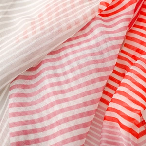 Detail shot of red and white striped linen fabric with semi-transparent texture and fringe