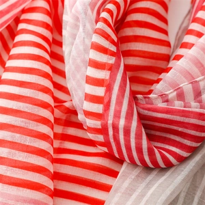Macro detail of the soft woven texture and fringe of a red striped cotton linen scarf