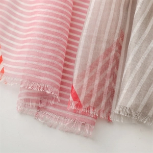 Macro detail of red and white striped scarf with natural frayed edges and soft texture