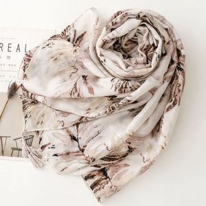 Detail of elegant leaf print scarf with tassels on white background with a magazine