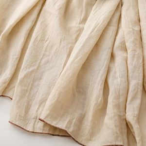 Nahaufnahme des beigefarbenen Baumwoll-Leinen-Schals mit eleganter brauner Rollsaumkante