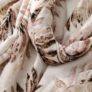 Detailed view of lightweight scarf with abstract brown leaf patterns and woven texture