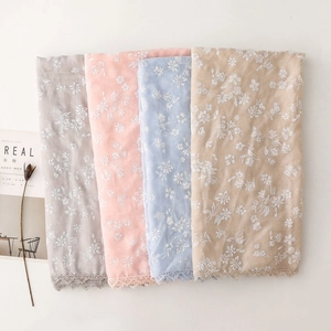 Close-up of floral embroidery and lace trim on soft cotton linen scarves in various colors
