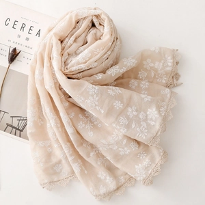 Close-up of beige cotton linen scarf with white floral embroidery and lace borders