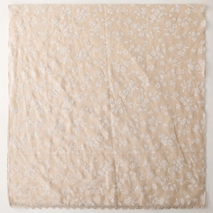 Detail of floral embroidery and delicate lace trim on soft beige linen-feel cotton scarf