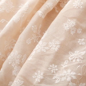 Close-up of soft pink cotton scarf featuring intricate white floral embroidery patterns