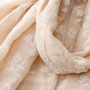 Macro detail of floral embroidery on beige cotton-linen scarf with fine fabric texture