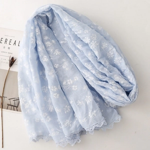 Detail of light blue cotton scarf featuring white floral prints and delicate lace edges