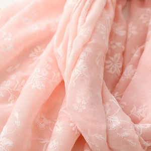 Macro shot of soft pink cotton scarf featuring delicate white floral embroidery details
