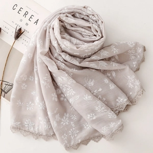 Close-up of light grey scarf with white floral embroidery and crochet lace edge details