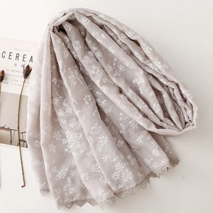 Macro detail of floral embroidery and retro lace border on light linen-feel scarf