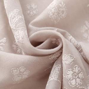Macro shot of embroidered floral patterns on soft beige cotton linen scarf fabric