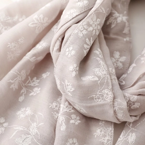Close-up of elegant white floral embroidery on a soft light purple linen scarf