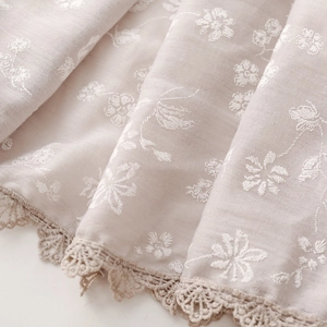 Detail of floral embroidery and delicate lace trim on soft cotton-linen fabric scarf