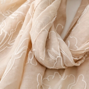 Dettaglio del ricamo floreale su sciarpa traspirante in cotone e lino color beige
