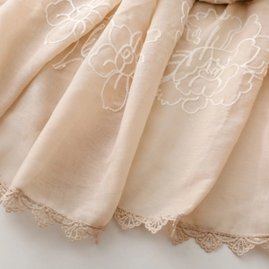 Dettaglio sciarpa di cotone beige con ricamo di rose bianche e bordo in pizzo