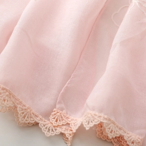 Dettaglio di sciarpa rosa chiaro con ricamo floreale e bordo in pizzo delicato