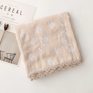 Détail d'une écharpe brodée beige avec des bords en dentelle et des motifs de roses