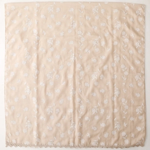 Détail de broderie florale et bordure en dentelle sur un foulard carré beige en coton-lin