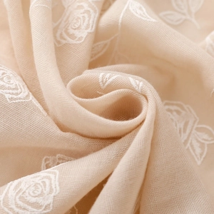 Gros plan sur un tissu doux en lin et coton beige avec broderie florale de roses blanches