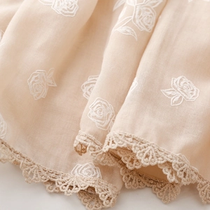 Détail macro de broderie de rose blanche et bordure en dentelle sur une écharpe en coton lin
