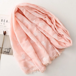 Gros plan d'une écharpe en coton rose avec broderies de roses et bordure dentelle