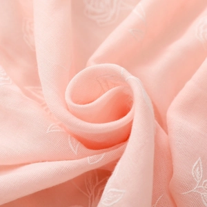 Gros plan d'une écharpe en coton rose doux avec broderie de roses blanches et texture de gaze
