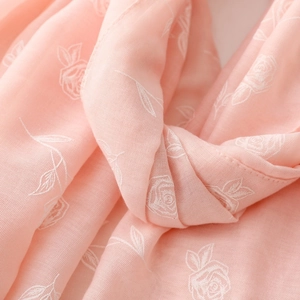 Gros plan d'une écharpe rose doux aspect lin avec broderie rose blanche et motif floral