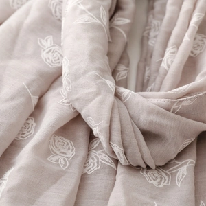 Détail d'une écharpe en coton et lin avec broderie de roses blanches et texture douce