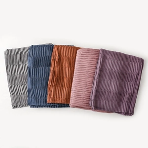 Detailed view of stacked pleated scarves in multiple colors showing soft fabric texture