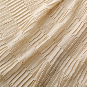Close-up of beige textured pleated fabric showing elastic crinkle details and soft wrinkles