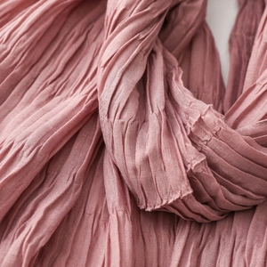 Close-up of pleated texture on a soft dusty rose scarf showing fine crinkle fabric detail