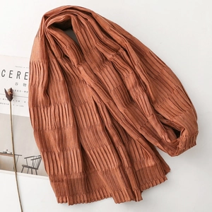 Detail shot of caramel pleated scarf with vertical texture and minimal lifestyle props