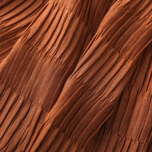 Close-up of caramel brown pleated scarf fabric texture with fine elastic wrinkles