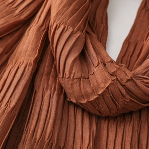 Detailed macro view of the rust-red pleated fabric texture and high-density vertical folds