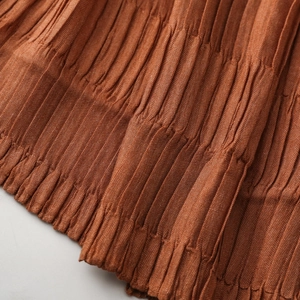 Macro detail of textured pleated scarf fabric in rusty brown with elastic smocked finish