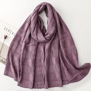 Close-up of deep purple pleated scarf with textured fabric next to a lifestyle magazine