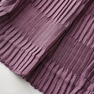 Macro shot of deep purple pleated fabric texture with detailed vertical wrinkled texture