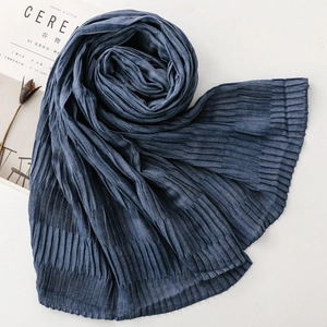 Detail of dark blue pleated scarf with textured fabric next to aesthetic dried flower