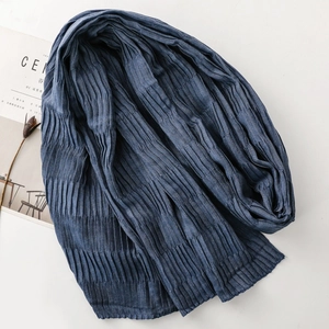 Detail of navy blue pleated scarf with textured fabric next to a lifestyle magazine
