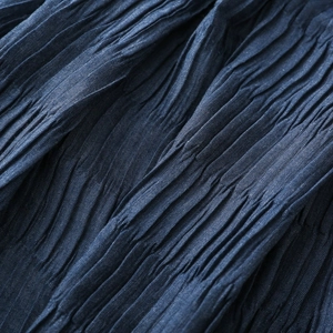 Detailed macro view of dark blue pleated fabric showing high-quality crinkle texture