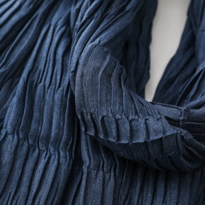 Macro detail of dark blue textured crinkle scarf fabric showing fine pleated workmanship