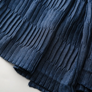 Macro detail of dark blue textured pleats on a soft autumn winter fashion scarf shawl