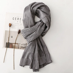 Detailed close-up of grey pleated scarf texture with minimalist props for autumn winter