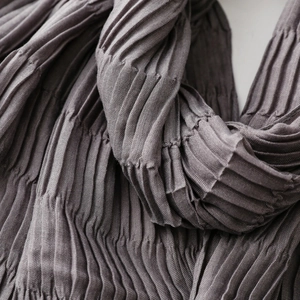 Close-up of pleated texture on a dark grey fashion scarf with ruched fabric details
