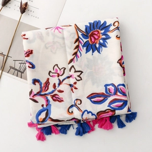 Detailed close-up of floral scarf texture with blue and pink fringes on a light fabric