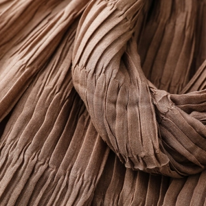 Detailed macro view of deep brown crinkled texture fabric for warm winter scarves